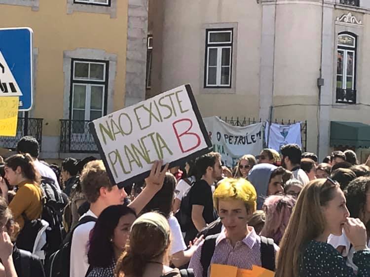 Jovens manifestantes com cartaz Não Existe Planeta B em frente à Assembleia da República
